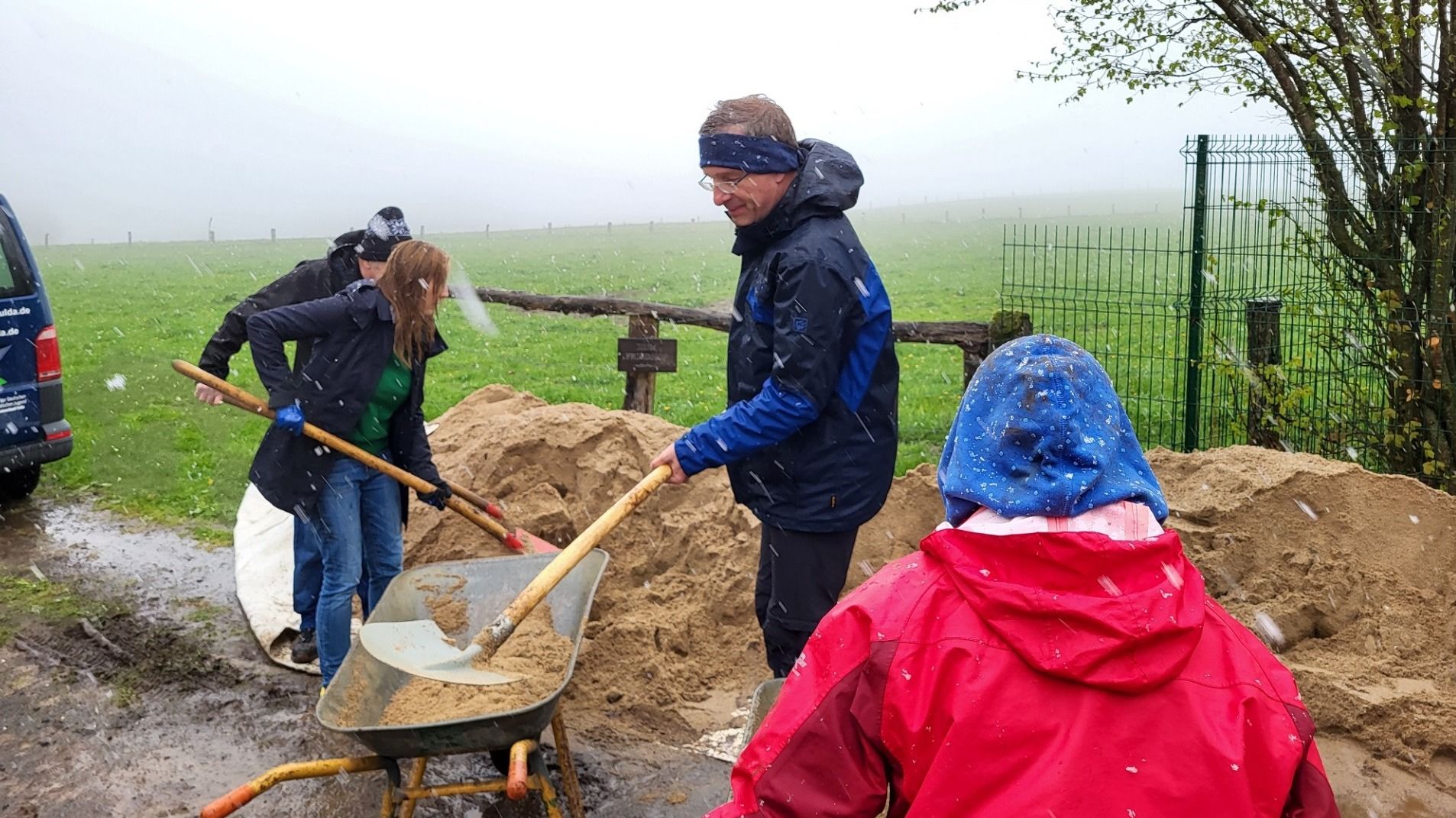 Beim 72-Stunden-Projekt der Kalbacher Jugendgruppe helfen Bischof Dr. Michael Gerber und Landtagspräsidentin Astrid Wallmann aktiv: Im Schneeregen wird Sand in eine Schubkarre geschippt. Foto: Bistum Fulda / Bertram Lenz